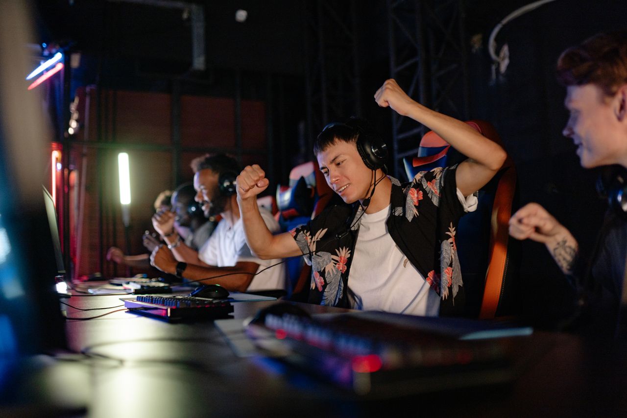Services Excited gamers celebrating a win in a competitive gaming tournament with headphones.
